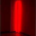LED corner floor lamp projecting solid red light onto both walls of a dark room corner with tripod base visible