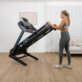 Woman using Lifespan Apex 2 at incline position with hands on handrails in home fitness setting