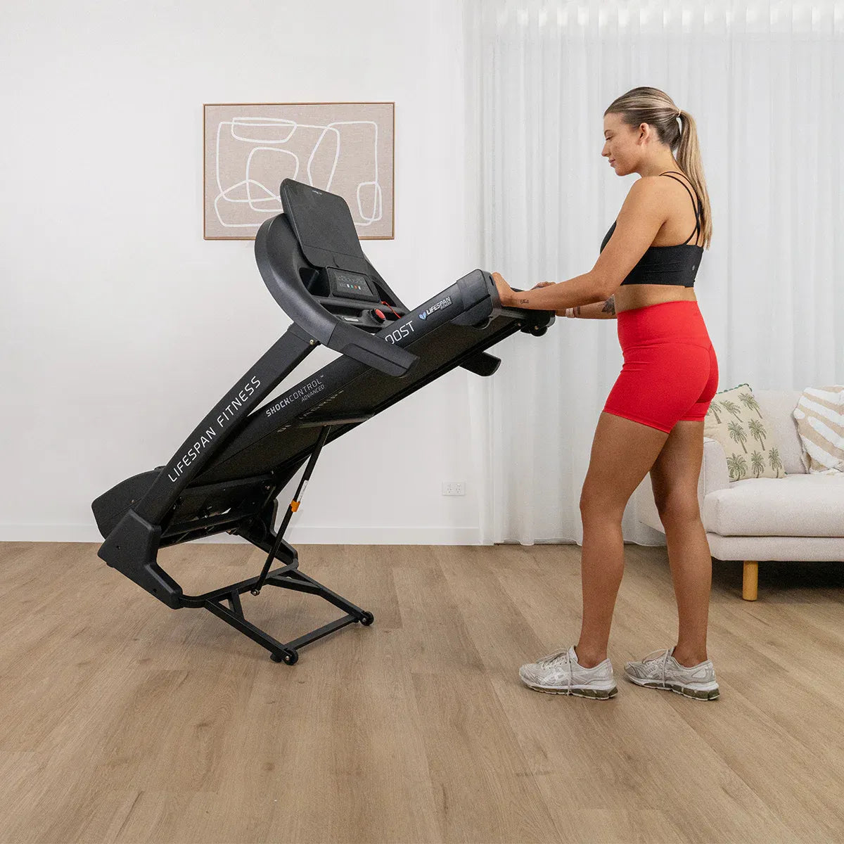 Woman using Boost 2 at incline position with hands on console in home gym
