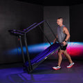 Male athlete training on Reformer 2 with blue and pink studio projection background