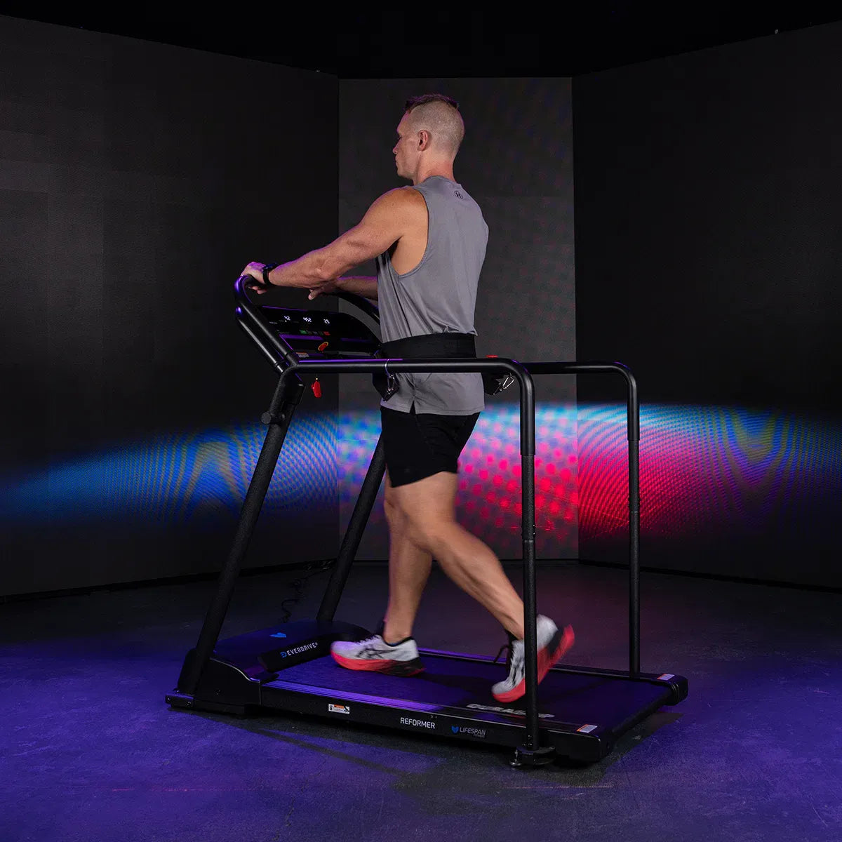 Runner in motion on Reformer 2 side view with colorful studio projection display