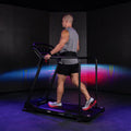 Athlete running on Reformer 2 with blue and purple studio projection lighting background