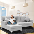 Woman sitting cross-legged on light grey corner sofa in modern living room with hexagonal wall art