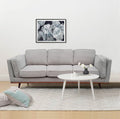 Light grey 3-seater sofa in living room with white round tripod coffee table and grey rug