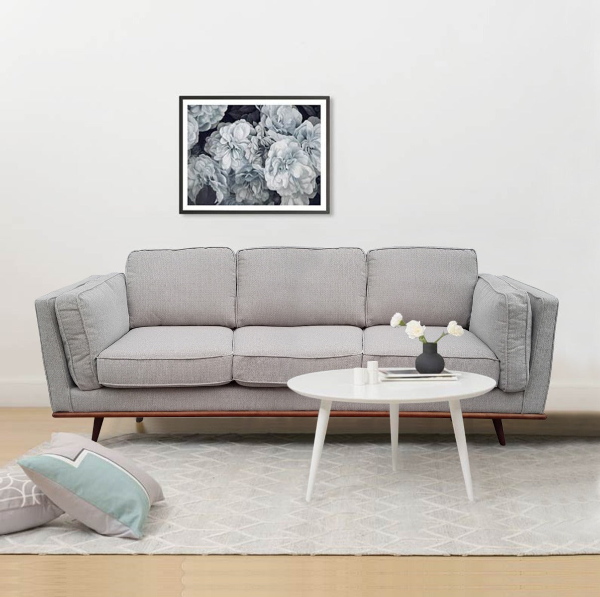 Light grey 3-seater sofa in living room with white round tripod coffee table and grey rug