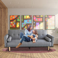 Woman and child sitting on light grey linen sofa bed in modern living room with colourful wall art