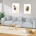 Light grey linen modular 3-seater sofa in Scandinavian-style room with abstract wall art and round tables