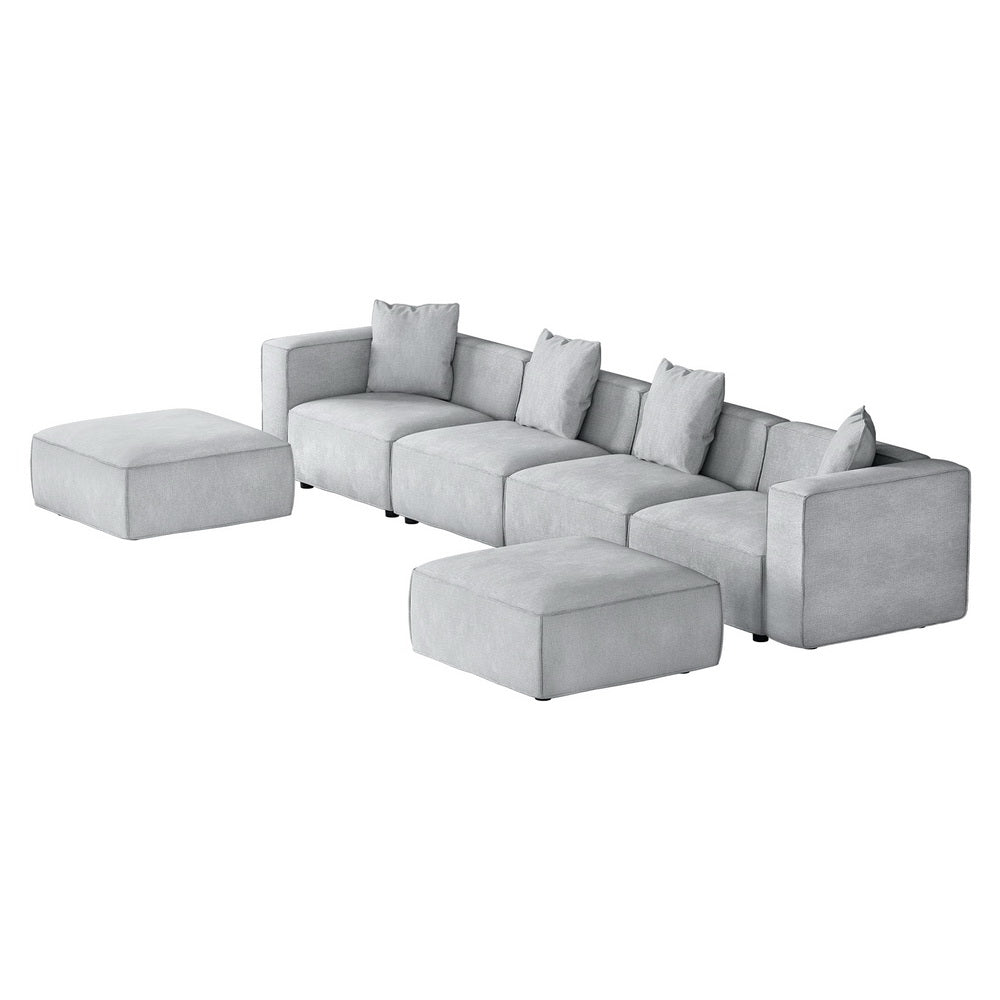 Light grey modular 4-seater sofa with left and right ottomans in bright living room with garden view