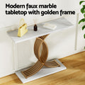 Marble console table with double curved gold arc base in entryway, styled with handbag, diffuser and books on top