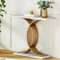 Marble console table with double-arc gold base against white paneled wall, styled with books, candle and potted plant