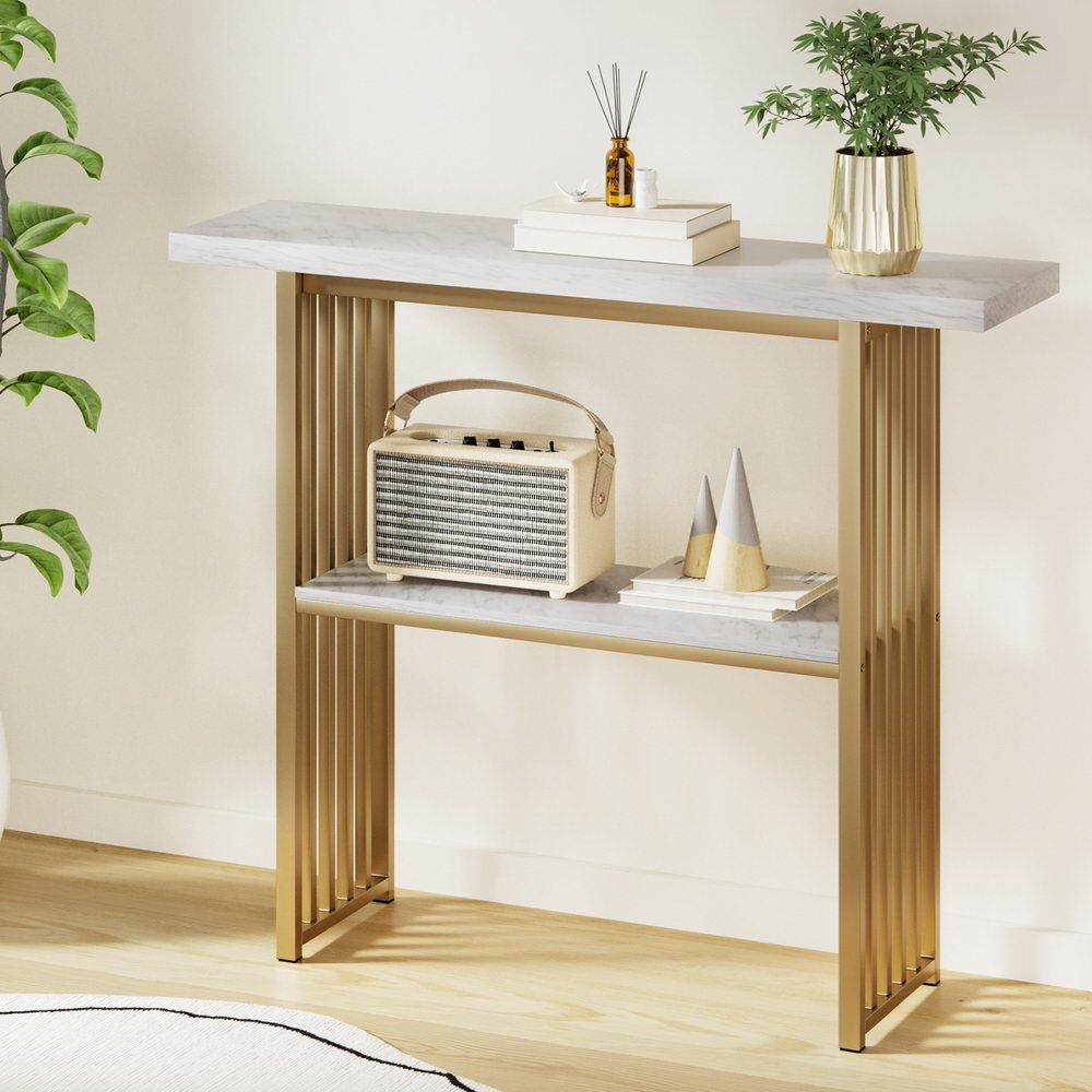 Marble console table with gold slat frame at angle, diffuser and plant on top, portable radio and decor on lower shelf