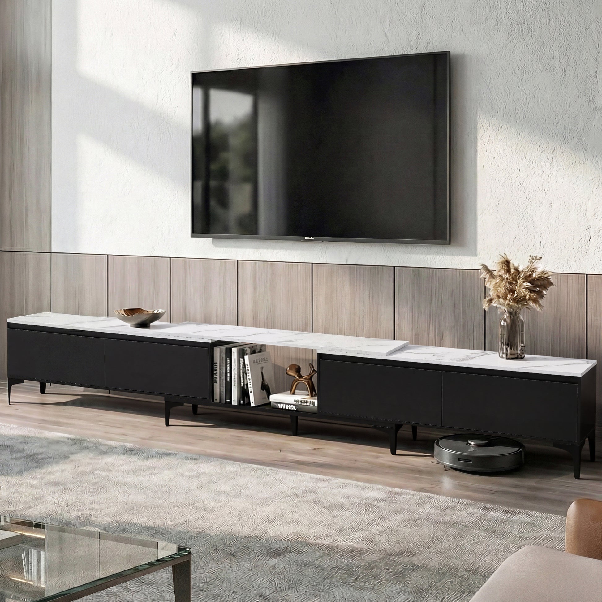 Black and white marble-top TV unit lifestyle with wood-panel wall vase and robot vacuum visible