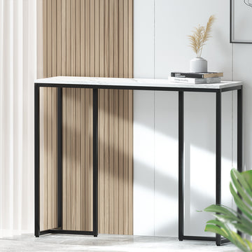 Marble-top console desk with black metal frame in room, styled with books and vase, wood-slat wall backdrop