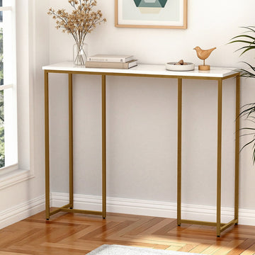 Console table with white marble-effect top and gold metal frame in room corner, styled with dried flowers and books