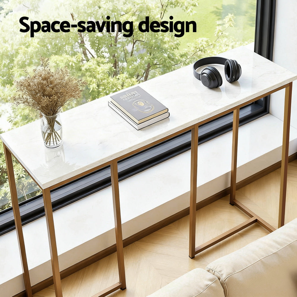 Marble-top console table with gold frame against window, books and headphones on top, text "Space-saving design"
