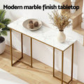 Console table with marble-effect top and gold frame near staircase, text 