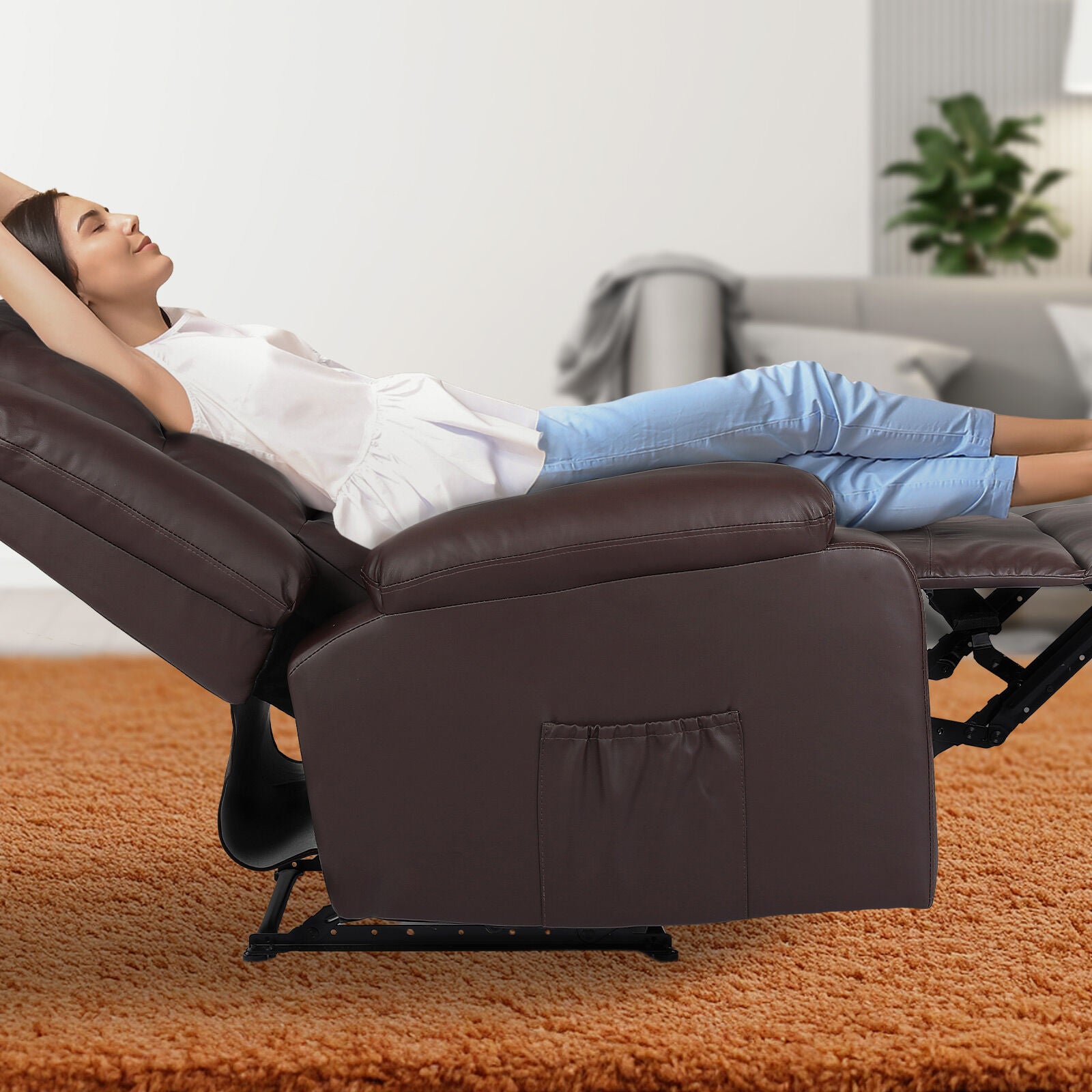 Woman fully reclined in dark brown PU leather recliner chair with footrest extended on orange rug in living room