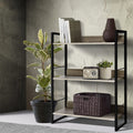 3-shelf metal frame bookcase in black and oak, styled with books, radio and wicker basket, beside rubber plant in grey room