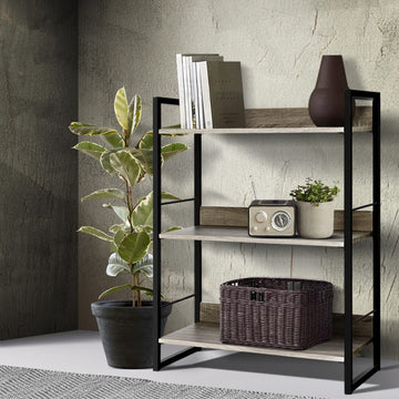 3-shelf metal frame bookcase in black and oak, styled with books, radio and wicker basket, beside rubber plant in grey room