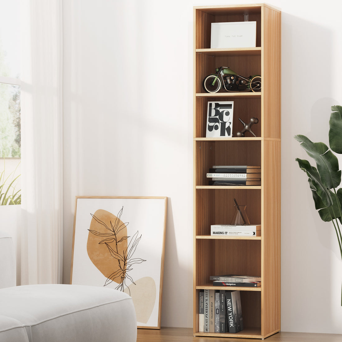 Tall narrow 7-shelf walnut bookcase styled with books and ornaments in bright living room beside armchair and plant