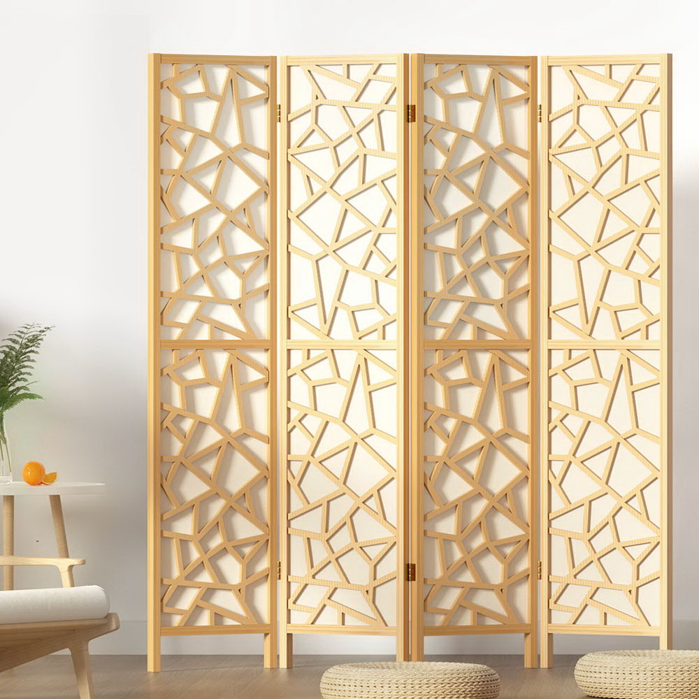 Natural pine 4-panel criss-cross geometric cutout room divider in lifestyle room with plant and round floor cushions