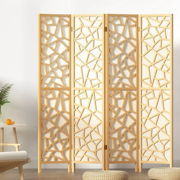 Natural pine 4-panel criss-cross geometric cutout room divider in lifestyle room with plant and round floor cushions