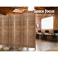 Natural 4-panel louvered wood room divider in industrial office with exposed ceiling beams and computer desks and brick wall