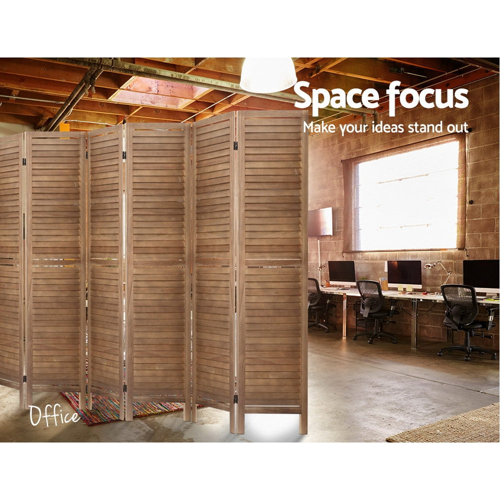 Natural 4-panel louvered wood room divider in industrial office with exposed ceiling beams and computer desks and brick wall