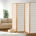 Natural pine 4-panel fabric grid shoji room divider in lifestyle room with cream sofa bamboo plant and wicker pouf
