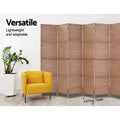 Natural 6-panel woven paper rope room divider in living room with yellow armchair and ZZ plant against white wall