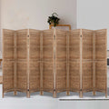 Natural 8-panel louvered wood room divider in lifestyle room with plant on wooden ladder shelf and cream rug on white floor