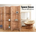 Natural 8-panel louvered wood room divider with shelves in bedroom lifestyle with books plant and round papasan chair
