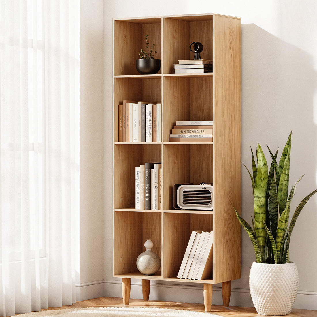 8-compartment cube bookcase in natural oak with tapered legs, styled with books and decor by sheer curtain window