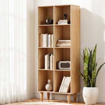 8-compartment cube bookcase in natural oak with tapered legs, styled with books and decor by sheer curtain window