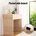 Natural oak console table with fluted side boards in windowed room, lamp and vase on top, close-up shows anti-slip base pad