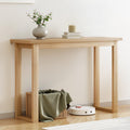 Natural oak console table in hallway with vase and candle on top, wicker basket and robot vacuum underneath