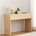 Natural oak console table with vertical wood slat side panels, lamp and glass vase with plant on top, warm room setting
