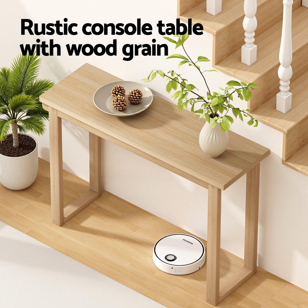 Natural oak console table by staircase with pine cones and vase on top, text "Rustic console table with wood grain"
