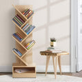 Natural wood 7-tier tree-shaped bookshelf filled with books, neutral room with wooden side table and potted heather