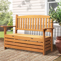 Natural wood garden storage bench on porch with woven rug, white weatherboard wall, terracotta pot and olive plant
