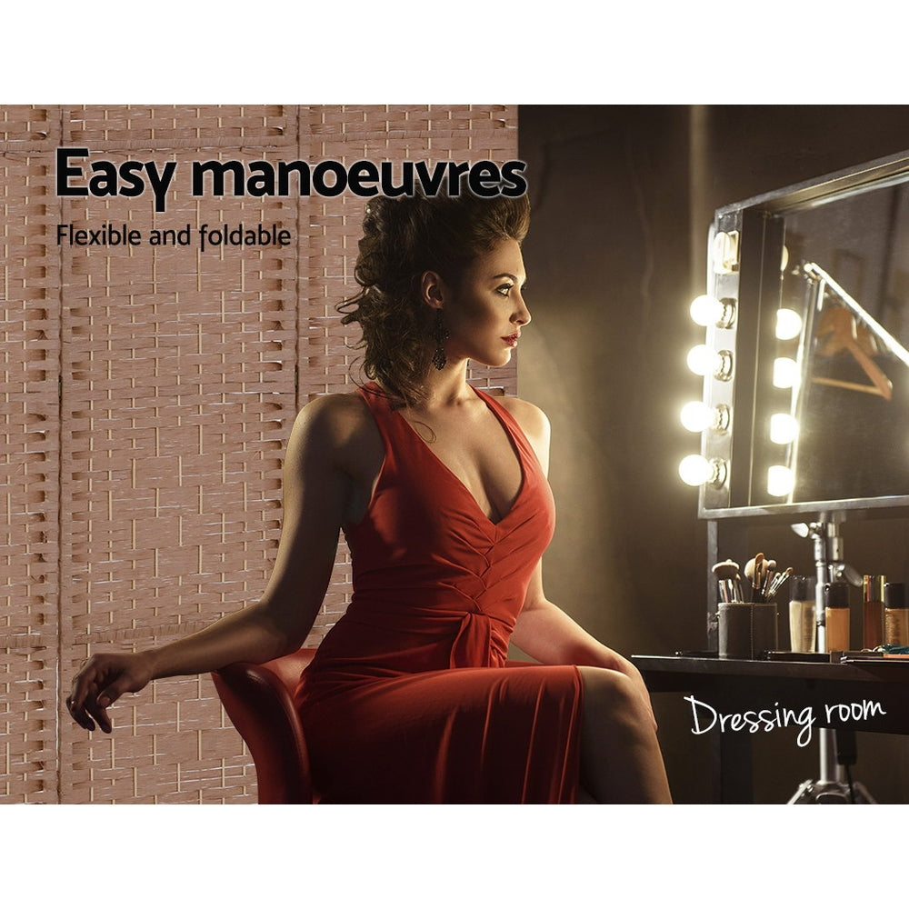 Natural woven paper rope room divider in dressing room with woman in red dress seated at lit Hollywood vanity mirror