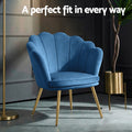 Navy blue velvet shell-back armchair in dark room with gold floor lamp and plant stand with A perfect fit text