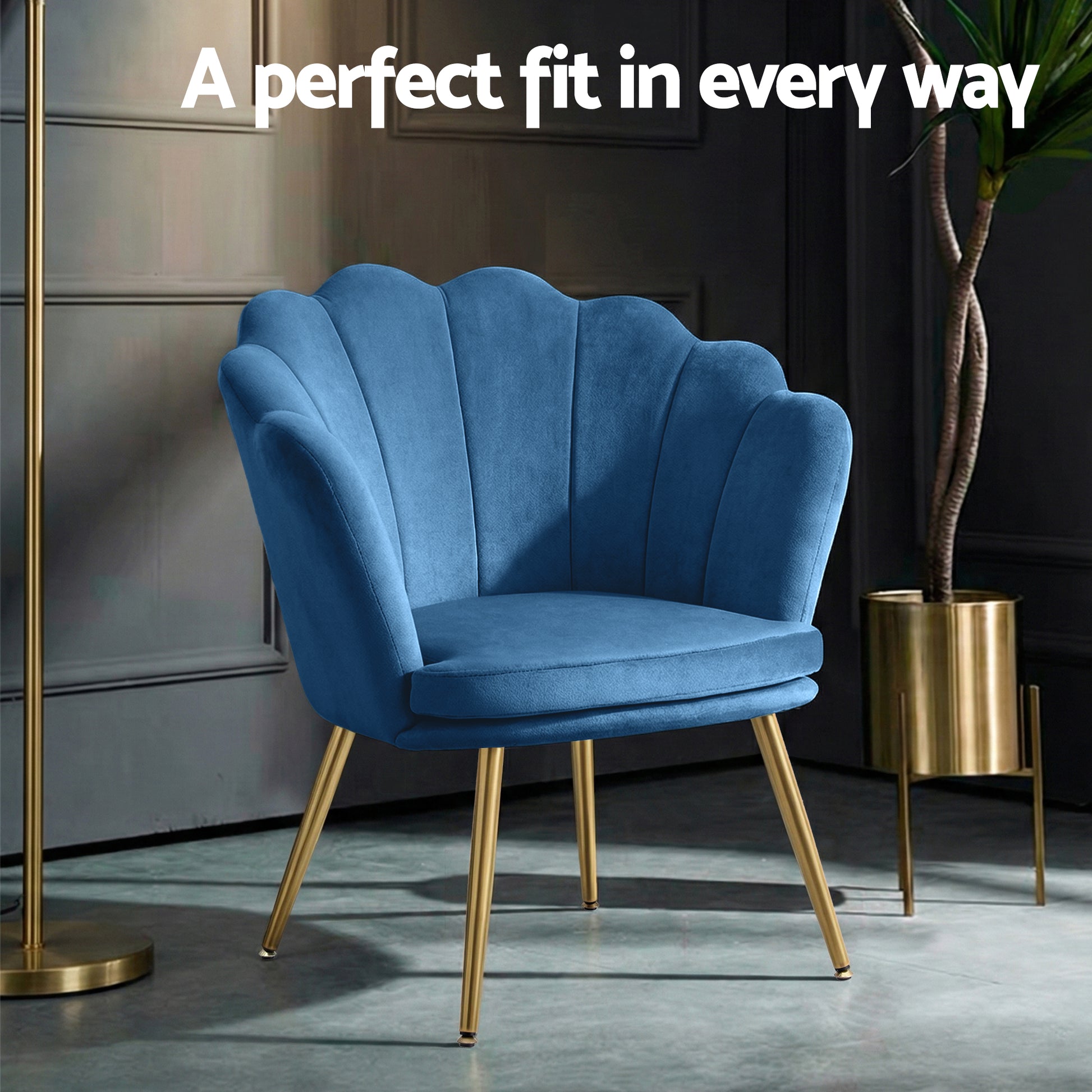 Navy blue velvet shell-back armchair in dark room with gold floor lamp and plant stand with A perfect fit text