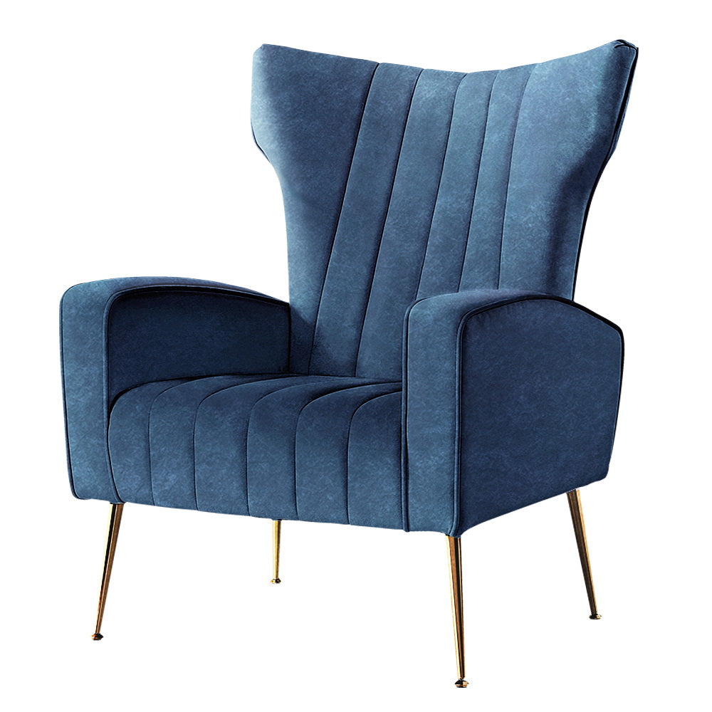 Navy blue velvet wingback armchair with vertical channel tufting and gold metal legs, three-quarter angle on white background