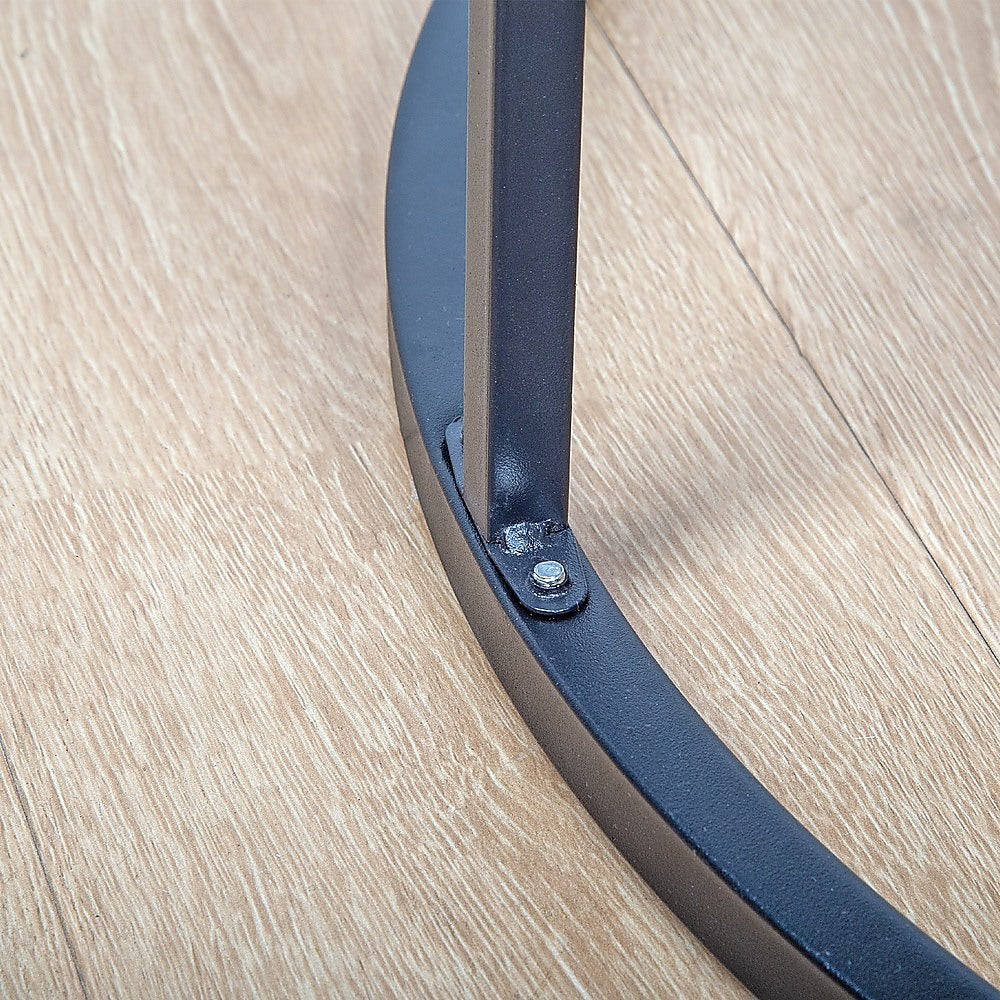 Close-up of black metal ring base joint where vertical support bar meets circular base, bolt visible, on wooden floor