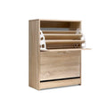 Oak two-door shoe cabinet three-quarter angle top door open showing empty tray lower door closed on white background