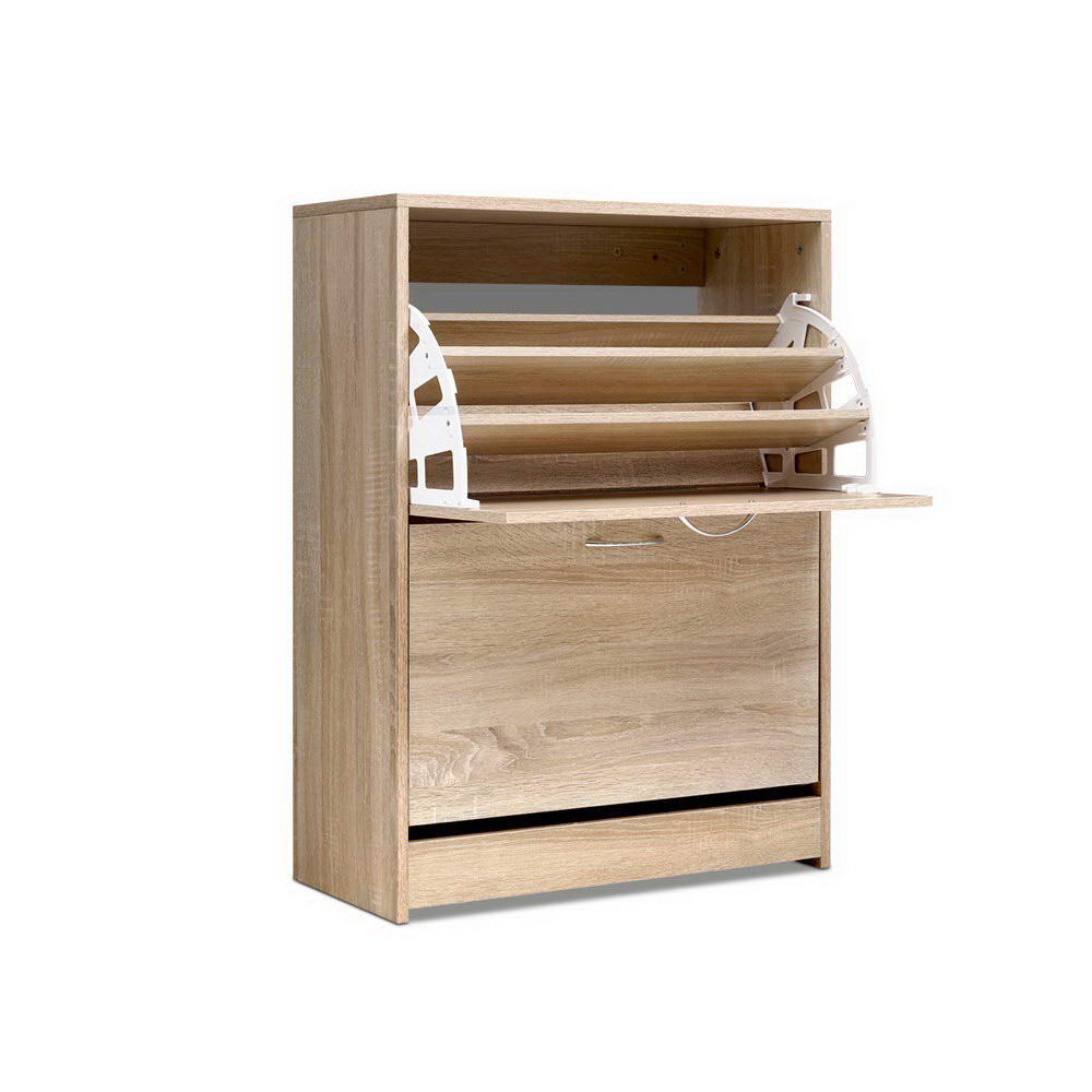 Oak two-door shoe cabinet three-quarter angle top door open showing empty tray lower door closed on white background