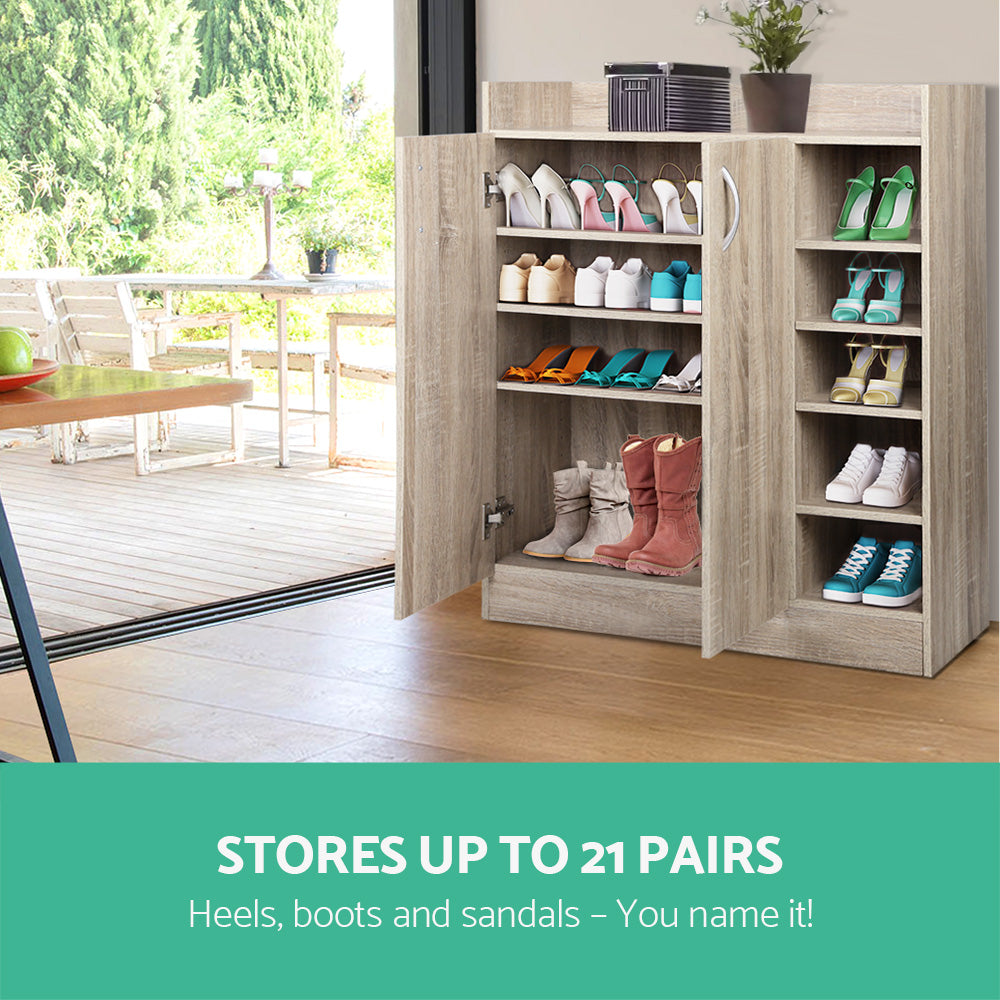 Oak shoe cabinet doors open showing 21 pairs of shoes heels boots and sandals stored inside with outdoor deck behind