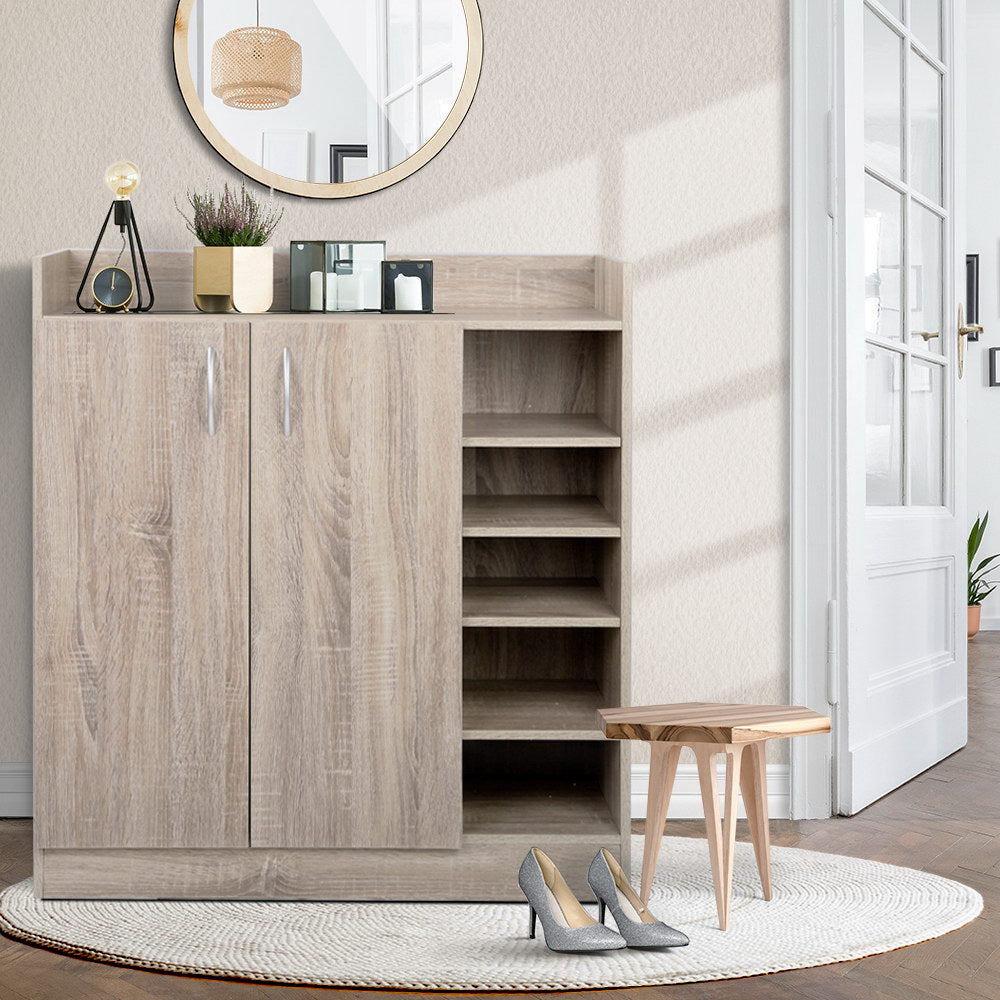 Oak finish 2-door shoe cabinet with side open shelves in entryway with round mirror and floor lamp