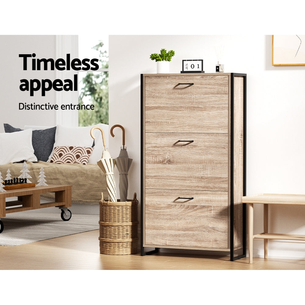 Oak finish three-tier flip-out shoe cabinet with black metal frame in living room lifestyle with umbrella stand and sofa